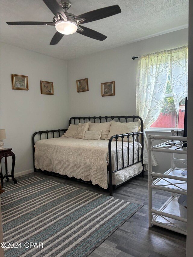 bedroom with dark hardwood / wood-style flooring, a textured ceiling, and ceiling fan