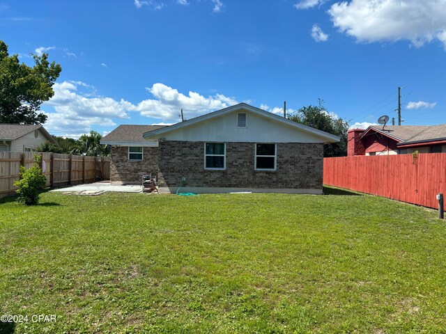 rear view of property featuring a patio area and a lawn