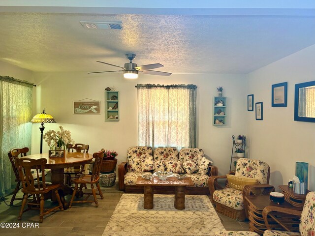 living room with a textured ceiling, wood-type flooring, and ceiling fan