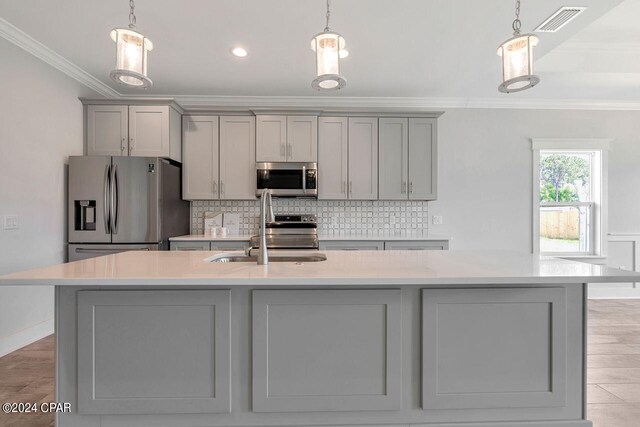 kitchen featuring pendant lighting, gray cabinets, stainless steel appliances, and a kitchen island with sink