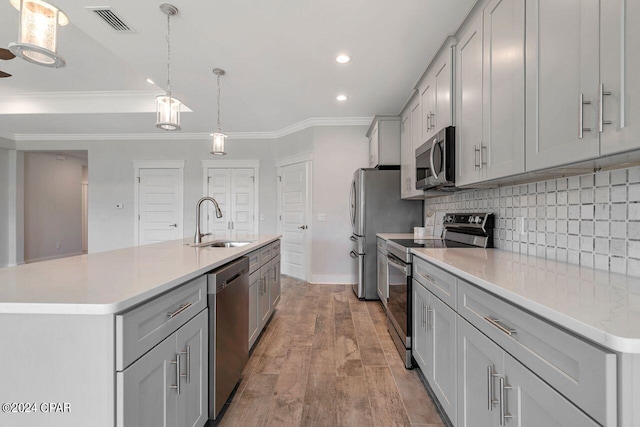 kitchen with sink, hanging light fixtures, stainless steel appliances, light hardwood / wood-style flooring, and a center island with sink