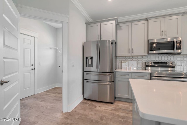 kitchen featuring gray cabinets, decorative backsplash, stainless steel appliances, and ornamental molding