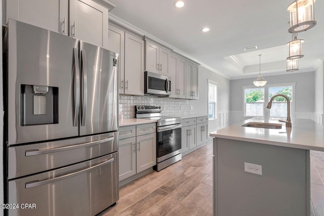 kitchen featuring gray cabinetry, a kitchen island with sink, sink, light hardwood / wood-style flooring, and appliances with stainless steel finishes