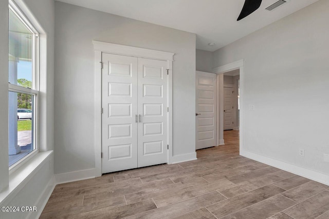 unfurnished bedroom with ceiling fan, light wood-type flooring, and a closet