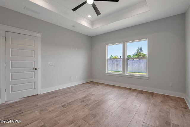 spare room featuring a tray ceiling, light hardwood / wood-style flooring, and ceiling fan