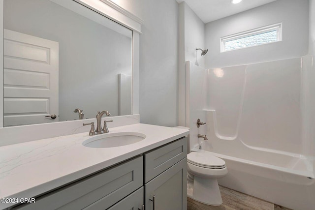 full bathroom with toilet, hardwood / wood-style floors, vanity, and tub / shower combination