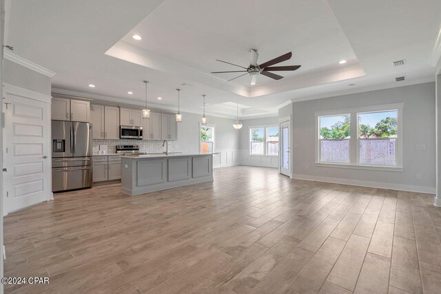 kitchen with appliances with stainless steel finishes, a tray ceiling, decorative light fixtures, and gray cabinetry