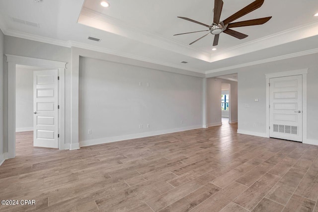 spare room featuring a raised ceiling, crown molding, ceiling fan, and light hardwood / wood-style floors