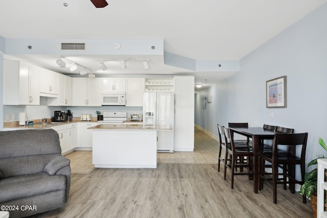 kitchen featuring light wood-type flooring, white appliances, white cabinetry, a kitchen island, and ceiling fan