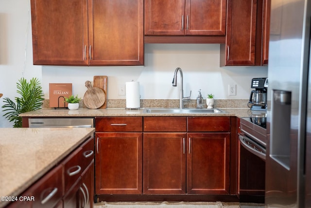 kitchen with light stone counters, stainless steel fridge with ice dispenser, sink, and oven