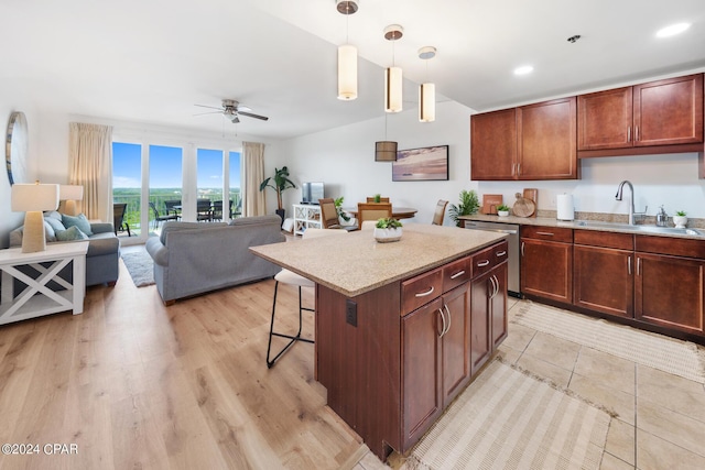 kitchen with sink, hanging light fixtures, a kitchen breakfast bar, a kitchen island, and stainless steel dishwasher