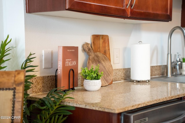 kitchen with dishwasher, sink, and light stone countertops