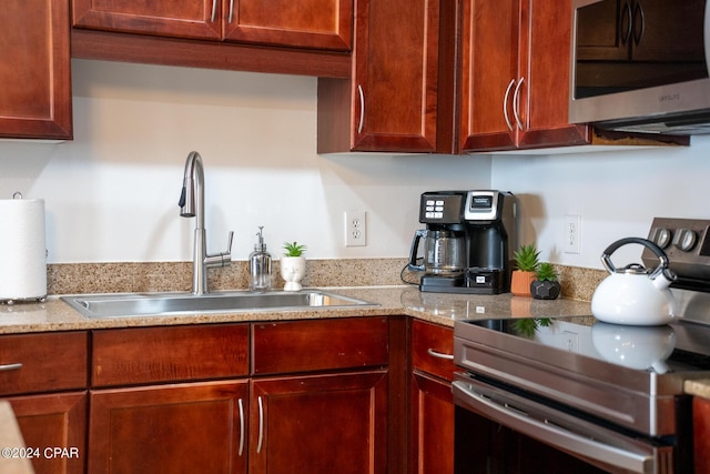 kitchen with appliances with stainless steel finishes, sink, and light stone counters