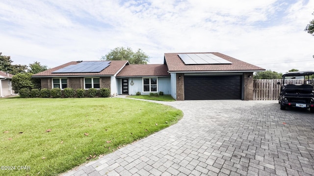 ranch-style home featuring solar panels, a garage, and a front lawn