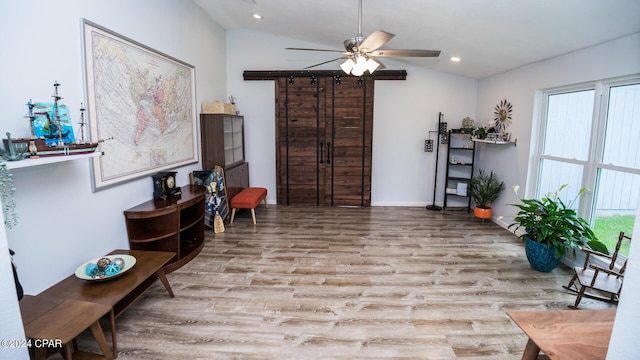 living area with ceiling fan, plenty of natural light, light wood-type flooring, and vaulted ceiling