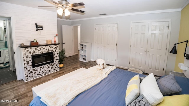 bedroom with a fireplace, dark hardwood / wood-style floors, ceiling fan, and crown molding