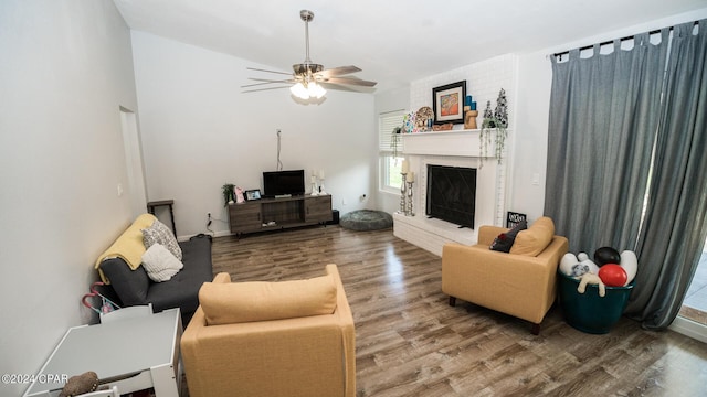 living room featuring a fireplace, wood-type flooring, and ceiling fan