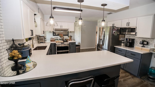 kitchen featuring stainless steel appliances, white cabinetry, hanging light fixtures, and dark wood-type flooring