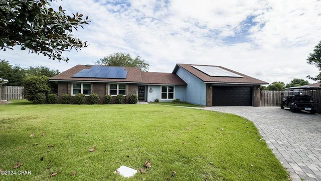 ranch-style house with solar panels, a garage, and a front lawn