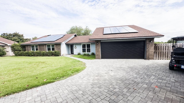 single story home featuring a garage, a front yard, and solar panels