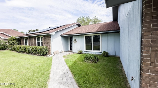 ranch-style home with a front yard and solar panels