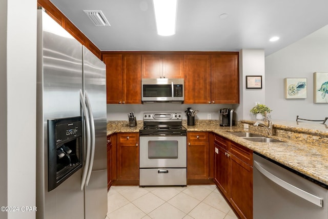 kitchen featuring sink, light stone countertops, light tile floors, and stainless steel appliances