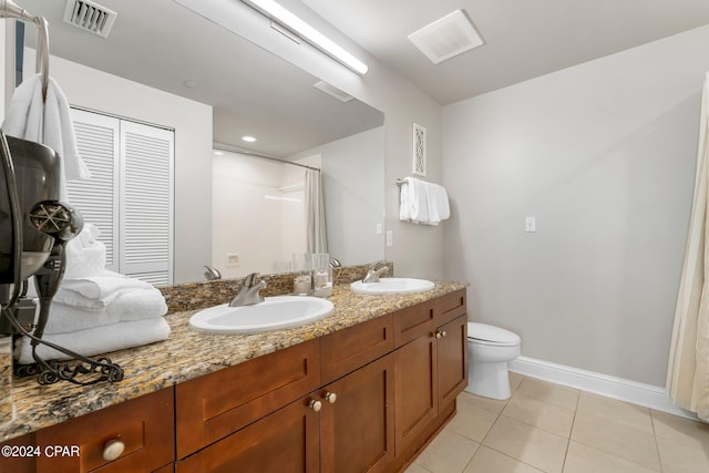 bathroom featuring tile floors, toilet, and double sink vanity