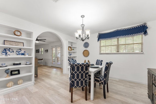 dining room featuring french doors, built in shelves, ceiling fan with notable chandelier, and light hardwood / wood-style floors