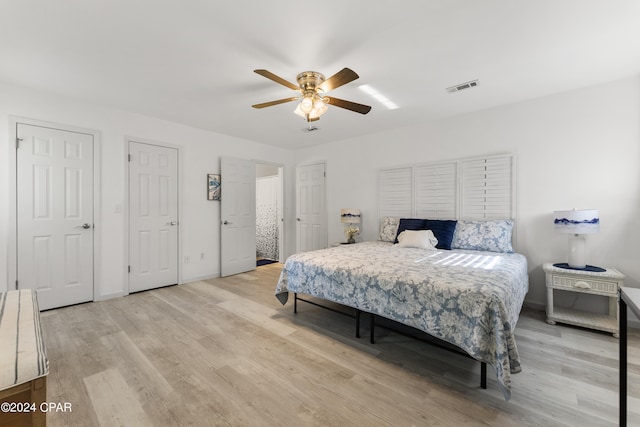 bedroom with two closets, ceiling fan, and light hardwood / wood-style floors