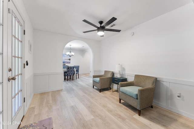 living area featuring ceiling fan with notable chandelier and light hardwood / wood-style flooring