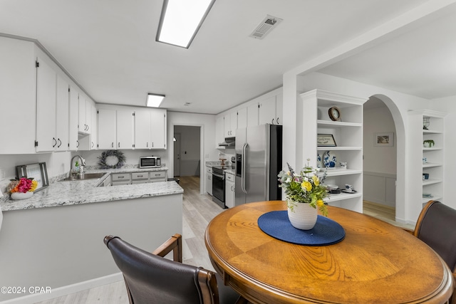 dining space featuring built in features, sink, and light wood-type flooring