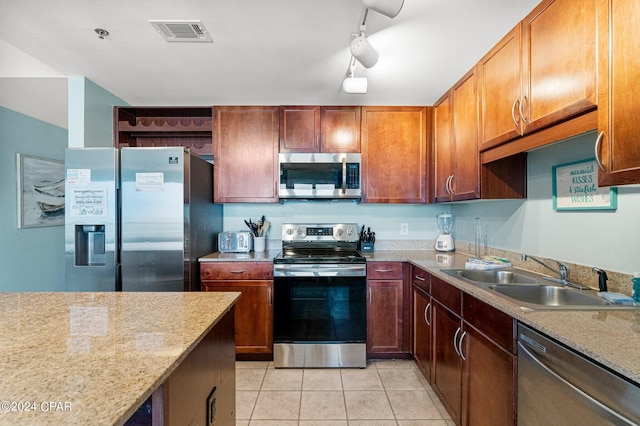 kitchen featuring light stone countertops, sink, stainless steel appliances, track lighting, and light tile patterned floors