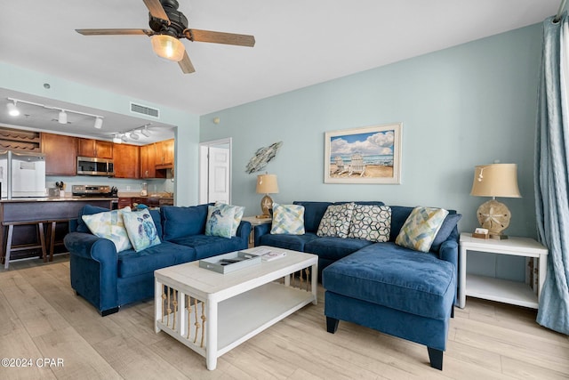 living room featuring rail lighting, light hardwood / wood-style flooring, and ceiling fan