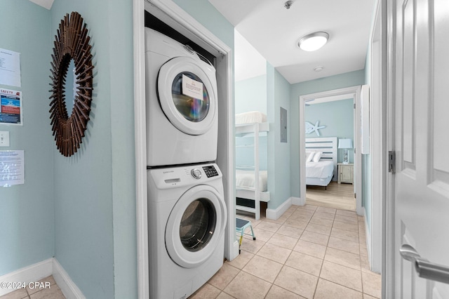 laundry room featuring stacked washing maching and dryer and light tile patterned flooring