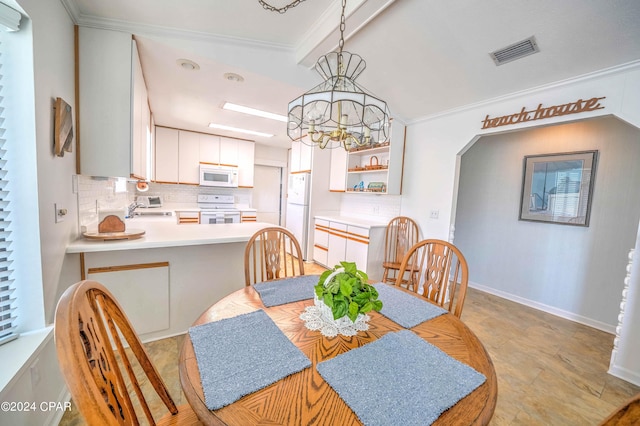 tiled dining area with an inviting chandelier, sink, and ornamental molding