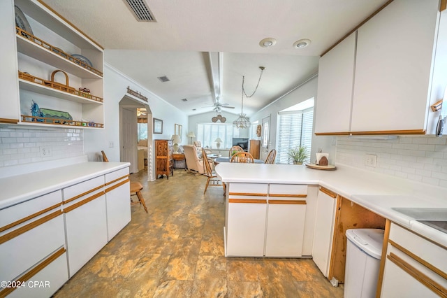 kitchen with kitchen peninsula, backsplash, lofted ceiling, white cabinetry, and ceiling fan