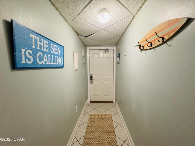 doorway with light tile patterned floors and a paneled ceiling