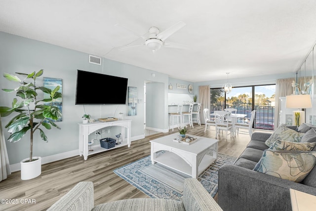 living room featuring ceiling fan with notable chandelier and wood-type flooring