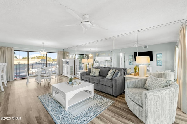 living room with ceiling fan, a textured ceiling, and hardwood / wood-style flooring