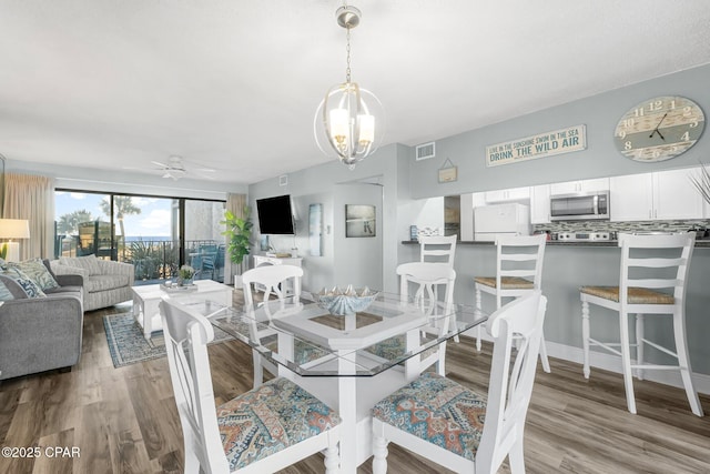 dining space featuring light hardwood / wood-style floors and ceiling fan with notable chandelier