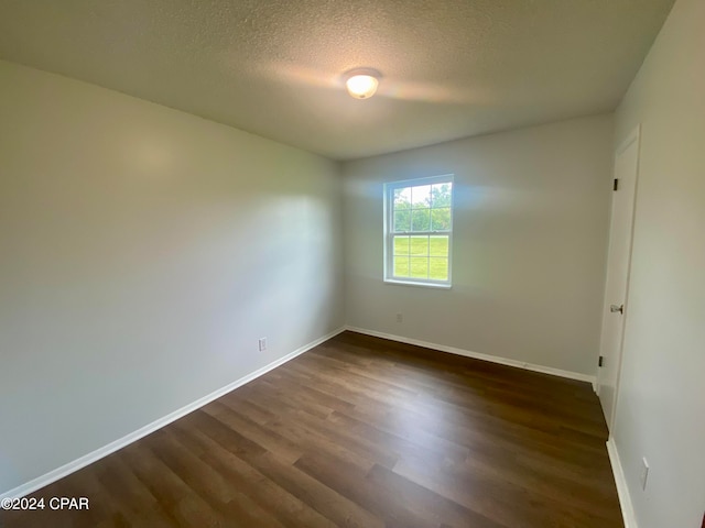 empty room with a textured ceiling and dark wood-type flooring