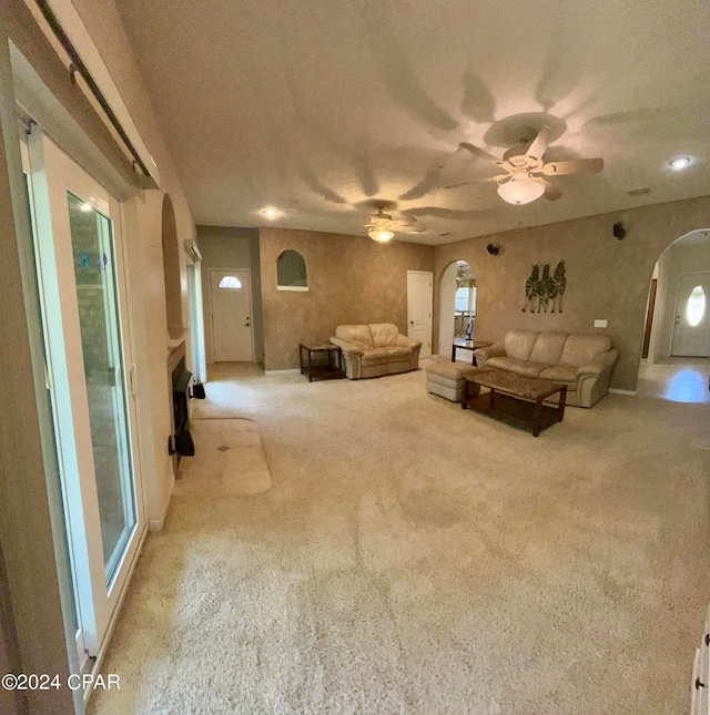 unfurnished living room featuring a textured ceiling, light colored carpet, and ceiling fan