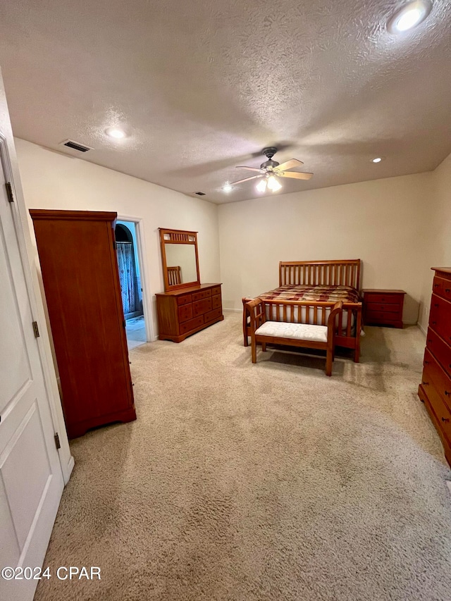 bedroom with light colored carpet and a textured ceiling