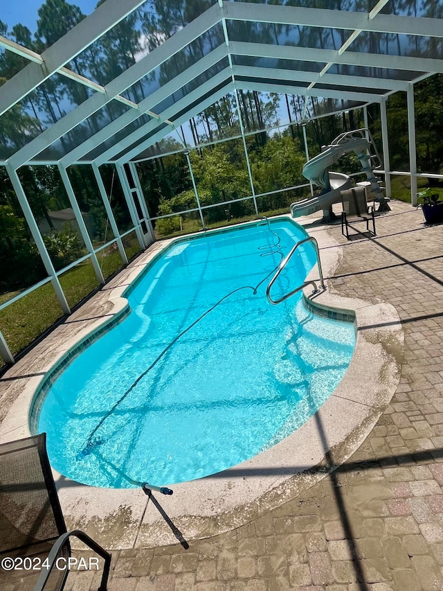 view of pool with glass enclosure, a patio, and a water slide