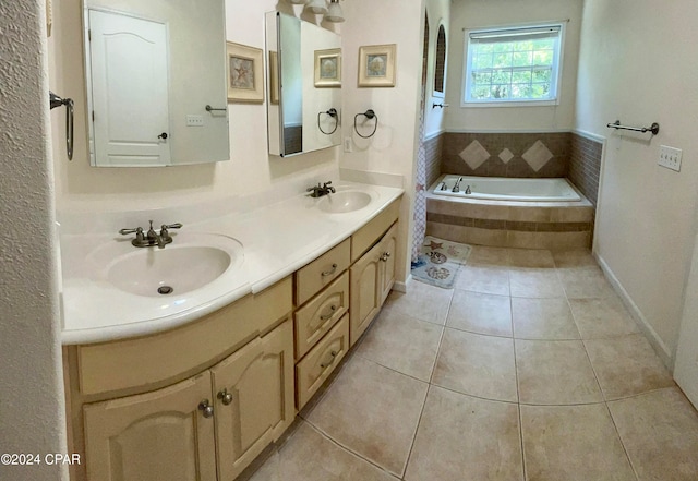 bathroom featuring tile patterned flooring, vanity, and tiled bath