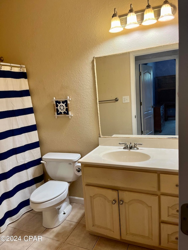 bathroom with toilet, vanity, and tile patterned floors