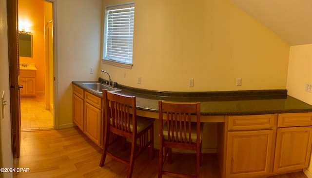 kitchen with sink, built in desk, lofted ceiling, and light wood-type flooring