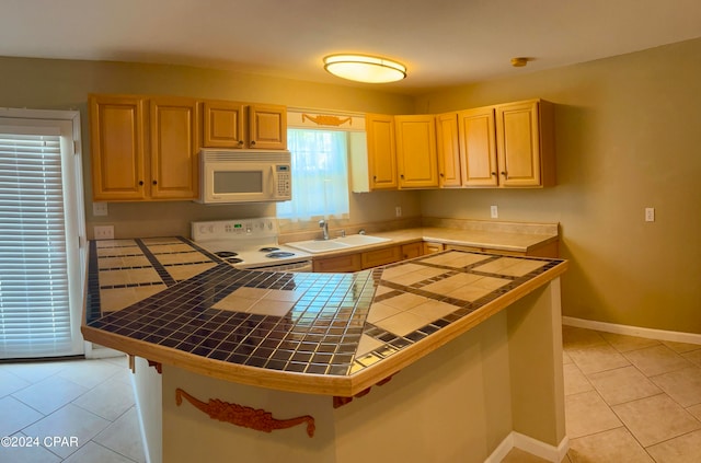 kitchen featuring white appliances, sink, light brown cabinets, light tile patterned floors, and tile countertops