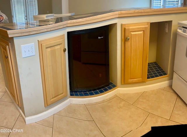 interior space featuring light tile patterned flooring, washer / dryer, and light brown cabinetry