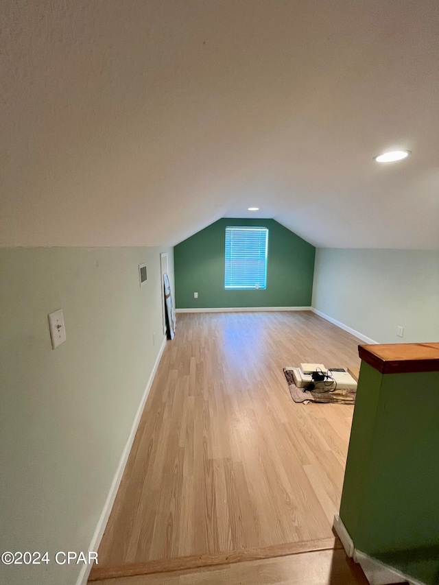 additional living space with hardwood / wood-style floors and lofted ceiling